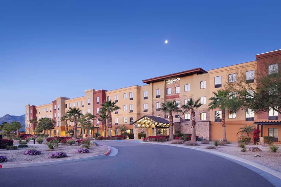 Colorful hotel exterior at dusk with palm trees and illuminated entrance
