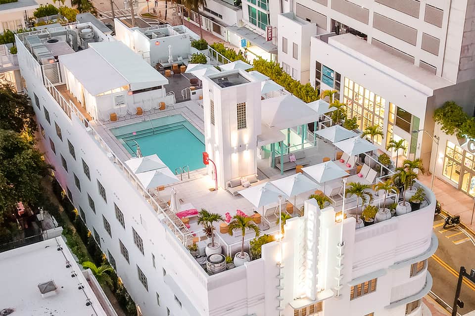 Rooftop pool deck with turquoise swimming pool, white lounge chairs, and modern white building architecture