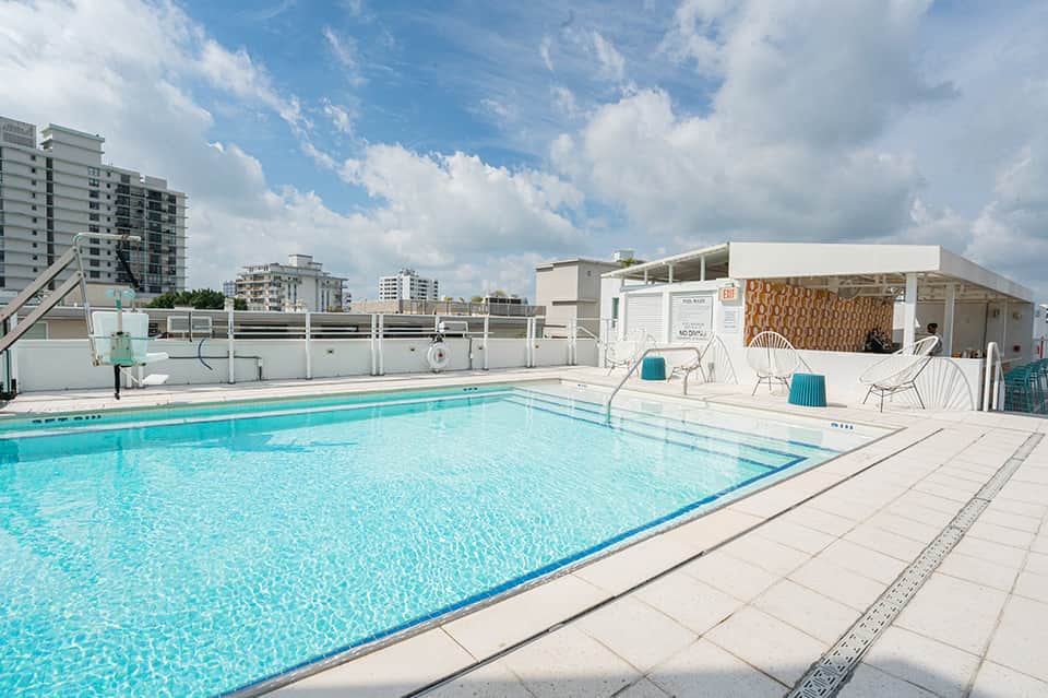 Rooftop swimming pool with white cabana, modern city skyline in background