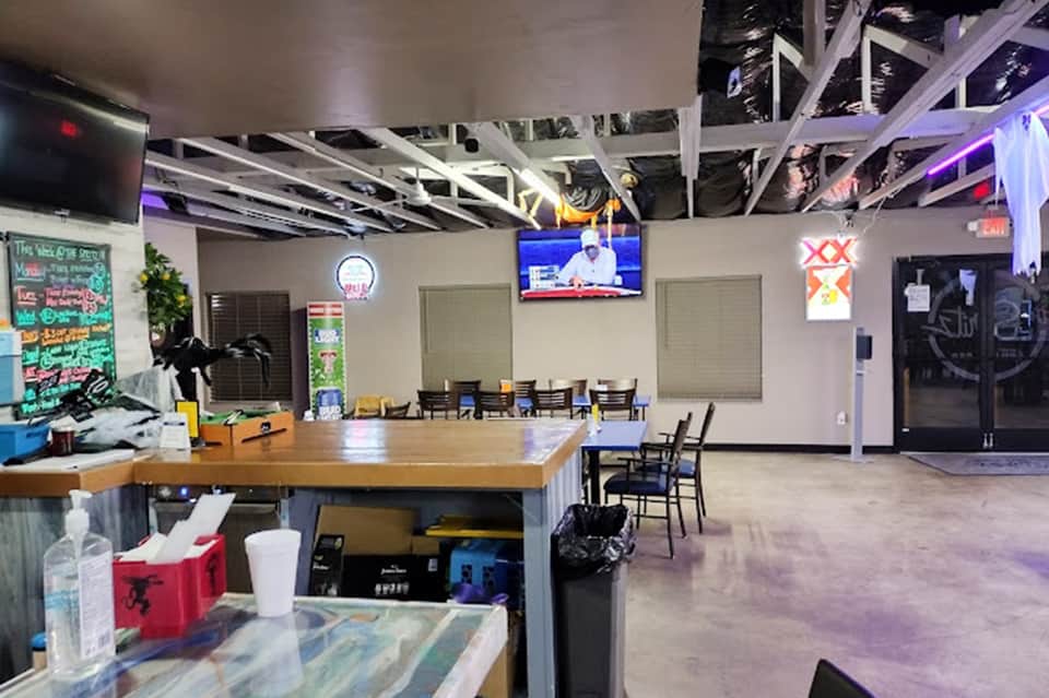 Modern event space interior with bar counter, seating area, and large screens for gatherings