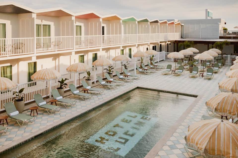 Colorful beachfront cottages with striped umbrellas surrounding a pool with spa text visible in the water