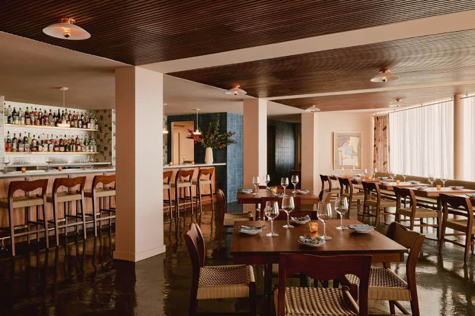 Upscale restaurant and bar with wood ceiling, dining tables, and extensive liquor collection behind counter