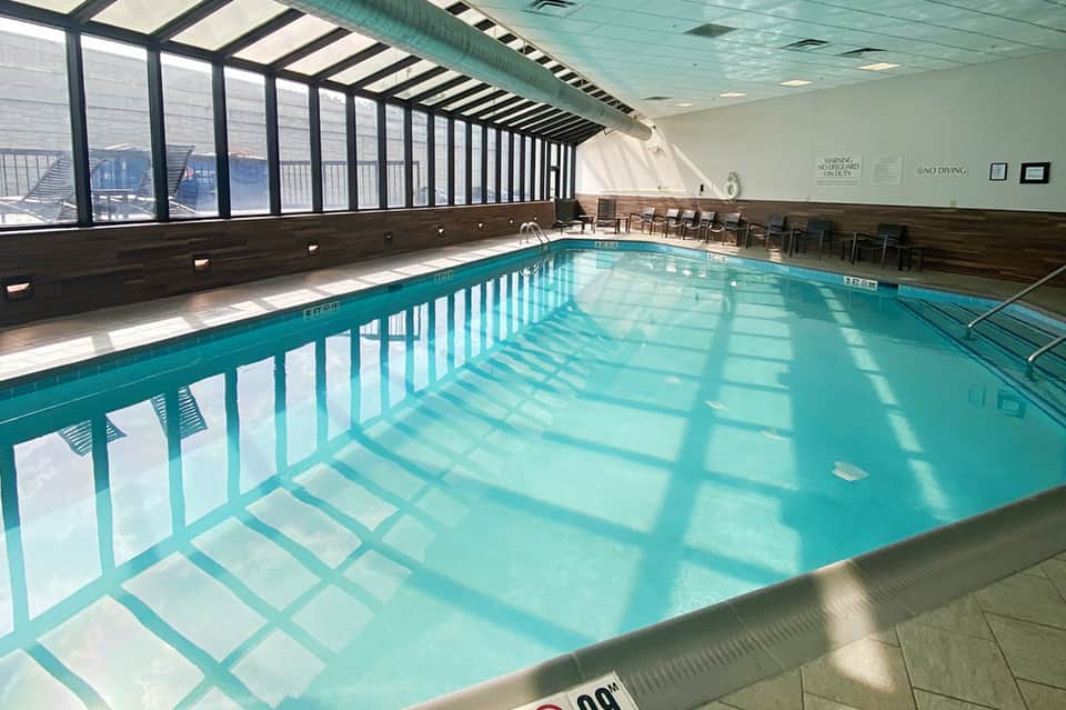 Indoor lap pool with clear turquoise water, large windows with city views, and lane dividers