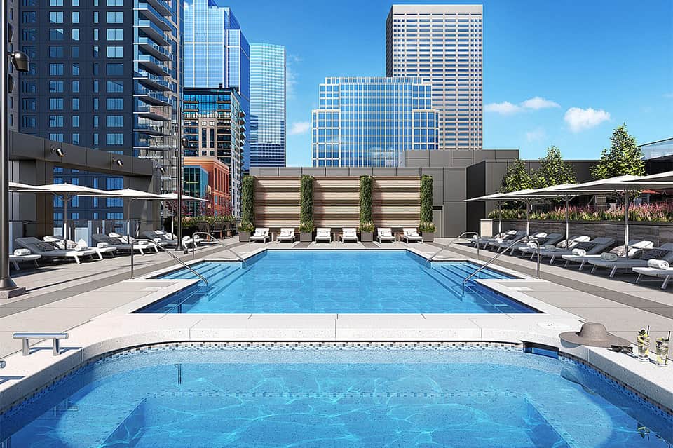 Modern urban rooftop pool with lounge chairs overlooking city skyline and high-rise buildings