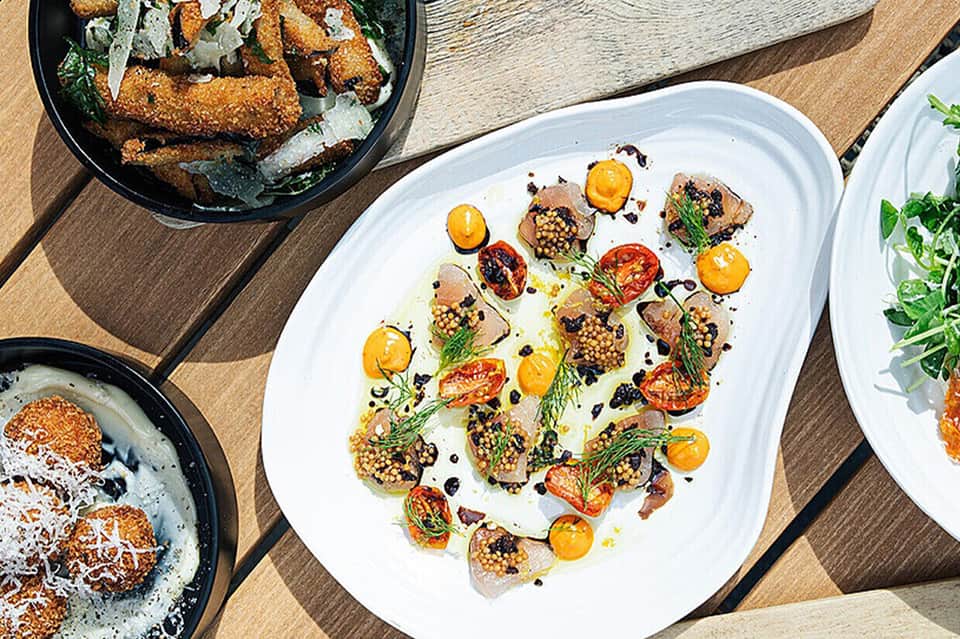 Overhead view of gourmet appetizers on white plate with colorful vegetables and garnish