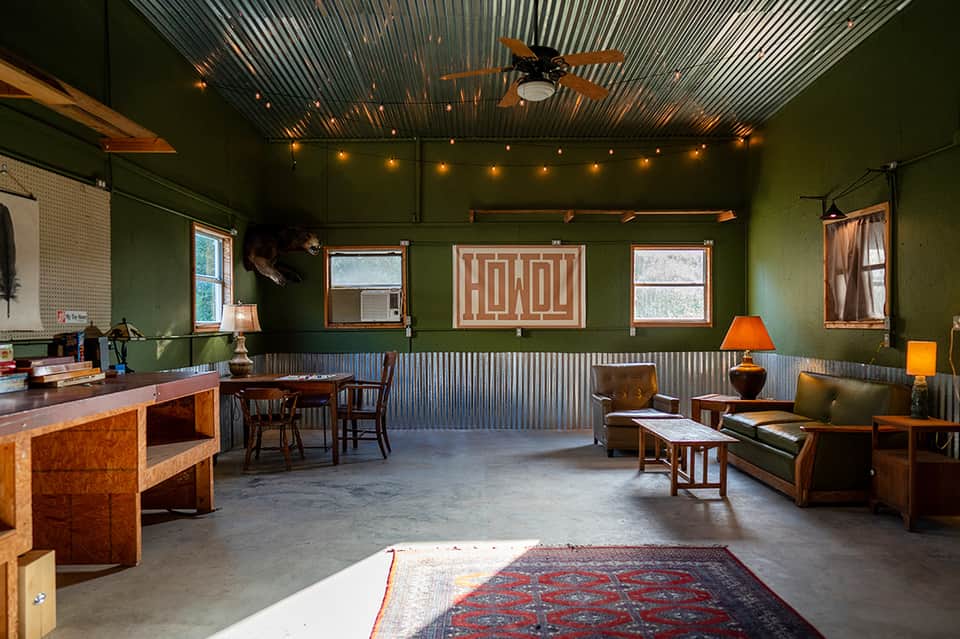 Industrial-style lounge with green walls, corrugated metal ceiling, and vintage furniture