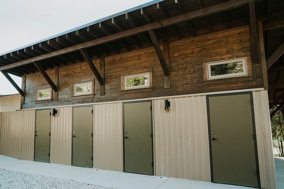 Modern wooden building exterior with multiple green doors and upper windows
