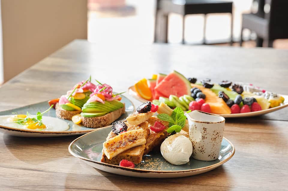 Plated gourmet dishes with fresh fruit garnishes and artistic presentation on restaurant tables
