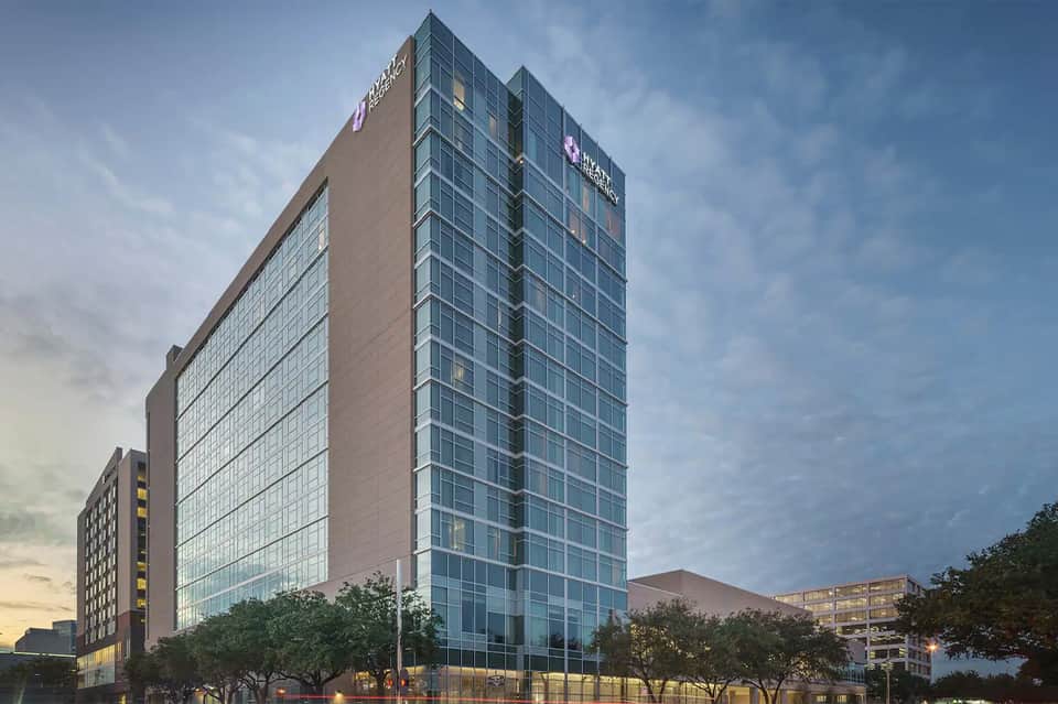 Modern multi-story hotel building at dusk with glass facade and illuminated signage