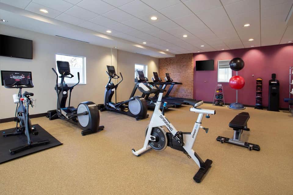 Modern fitness center with stationary bikes, ellipticals, treadmill, and pink accent wall