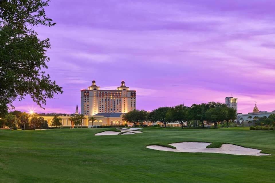 Luxury hotel on golf course at purple sunset with illuminated grounds