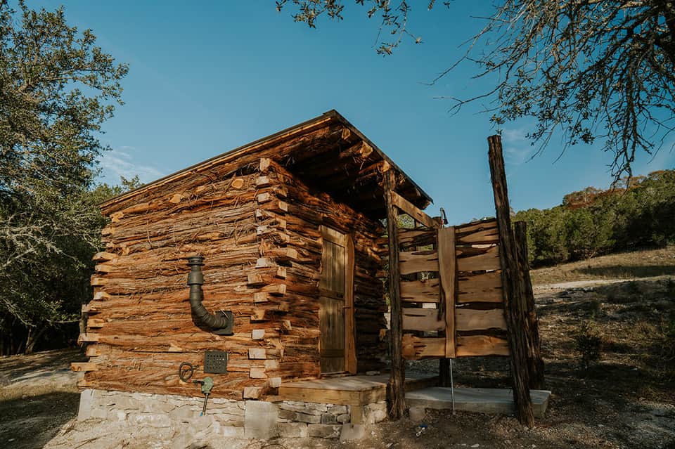 Historic log cabin with wooden fence structure in natural landscape setting