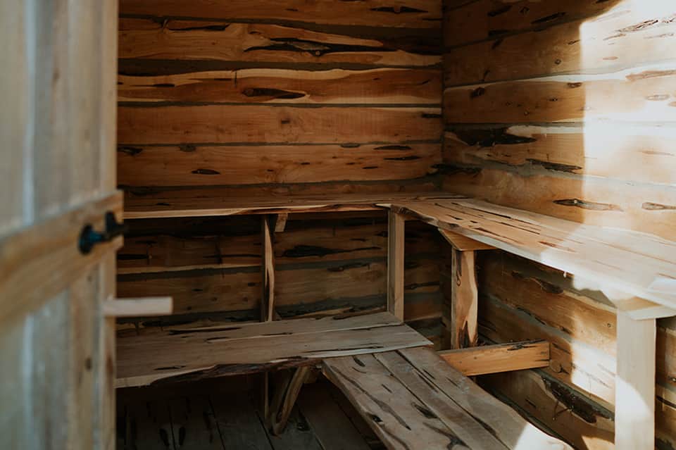 Rustic wooden sauna interior with benches and natural wood construction showing knots and grain