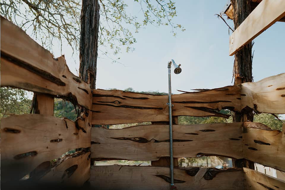 Wooden ranch fence with weathered beams and metal post against hillside landscape
