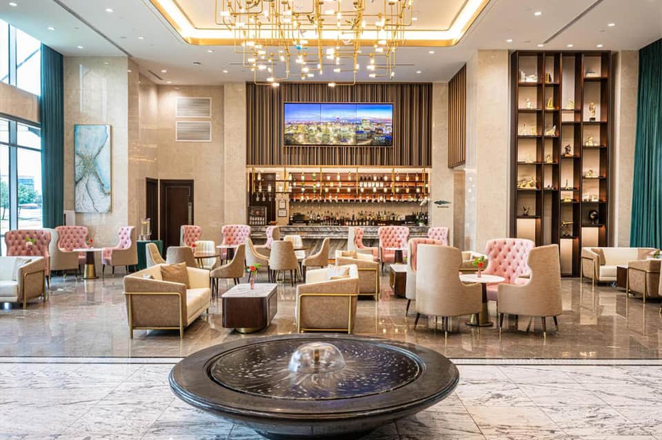 Luxury hotel lobby with bar, fireplace, chandelier, and elegant seating