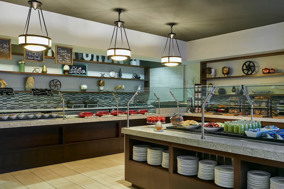 Modern bakery cafe with display cases, pendant lighting, and tiered shelving with decorative items