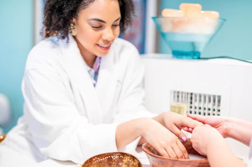 Dermatologist examining patient's skin with magnifying tool in clinical spa setting