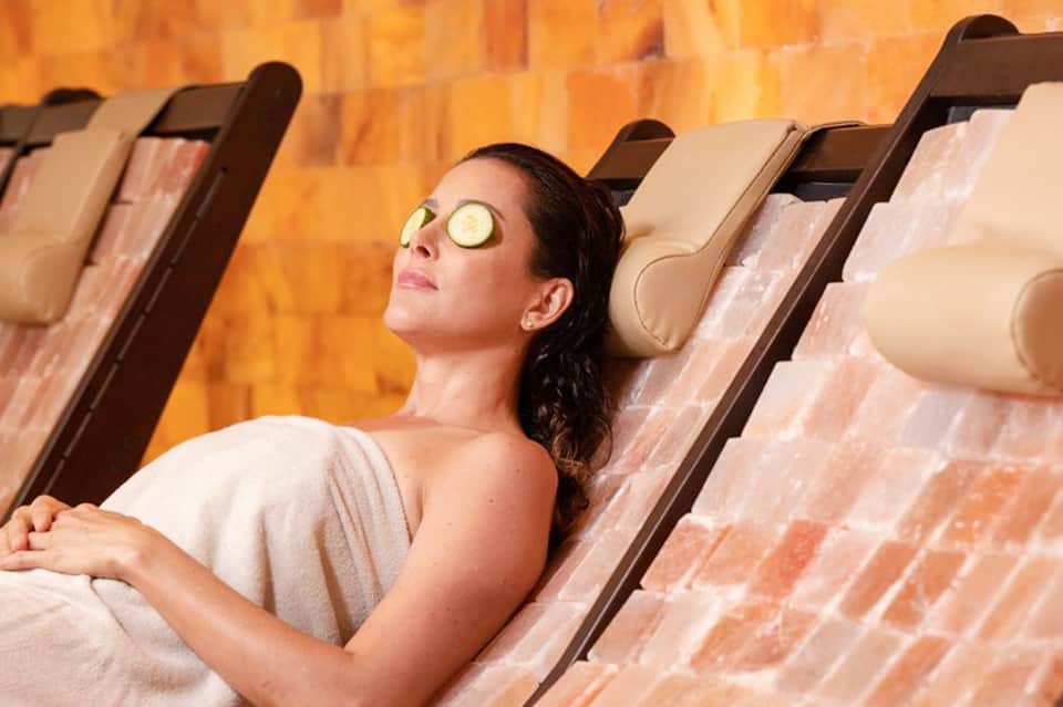 Woman relaxing poolside with cucumber eye mask and spa treatment