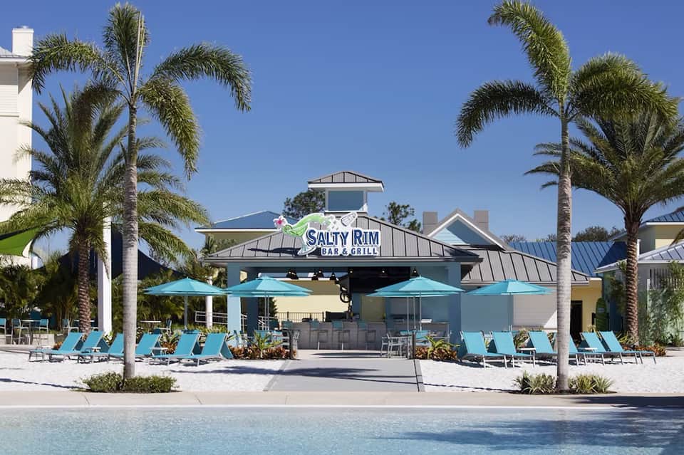 Salty Rim Bar & Grill with turquoise lounge chairs and palm trees under clear blue sky