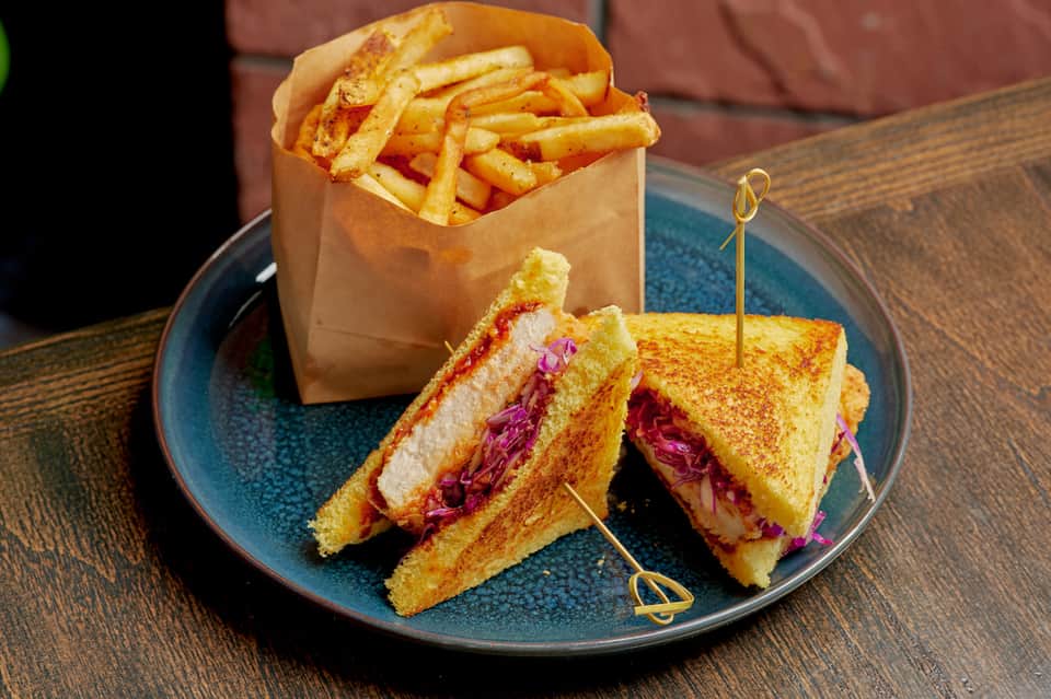 Gourmet sandwich with purple cabbage and fries served on blue plate at resort restaurant