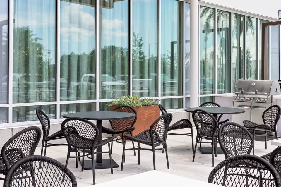 Outdoor patio with black mesh chairs and tables overlooking landscaped grounds