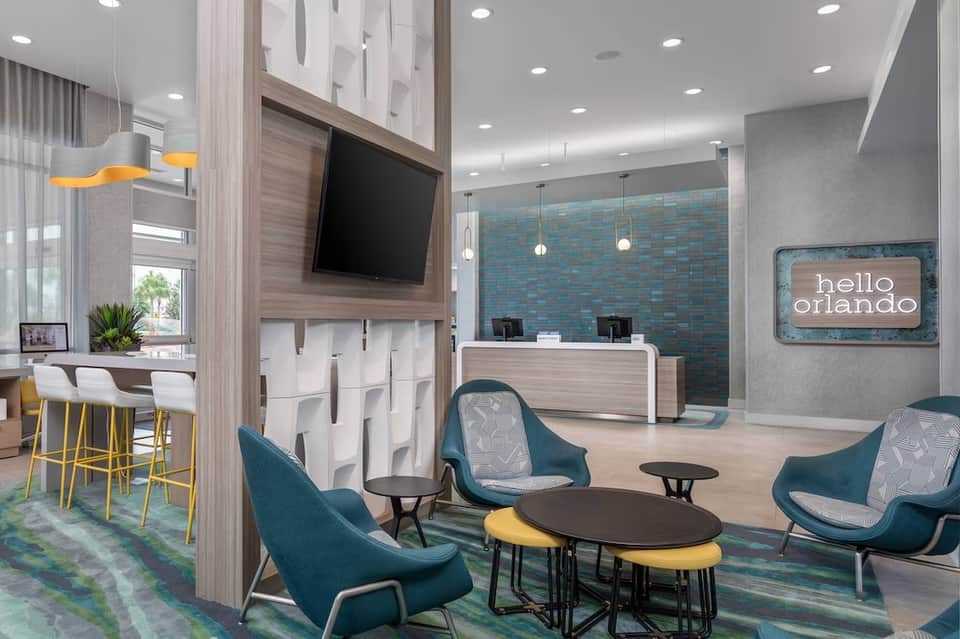 Contemporary hotel lobby featuring teal accent wall, reception desk, and lounge seating area