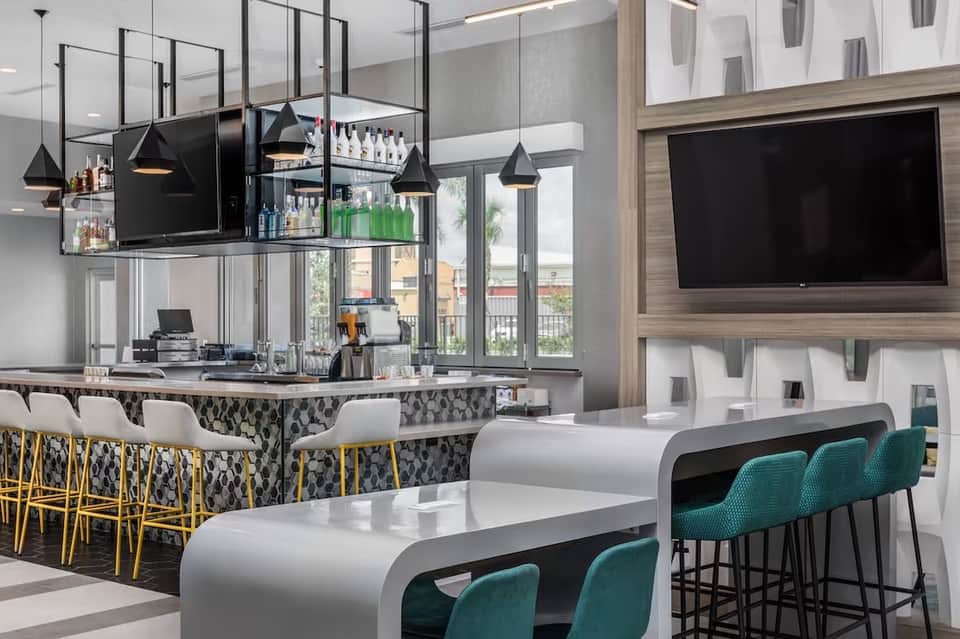 Contemporary bar lounge with suspended black pendant lights, patterned backsplash, and curved counter seating