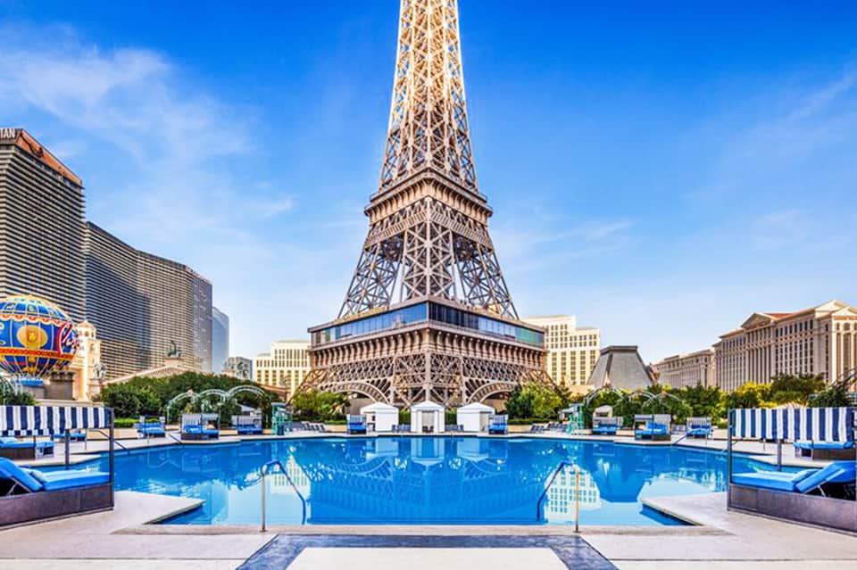 Resort swimming pool with Eiffel Tower replica backdrop and blue lounge chairs