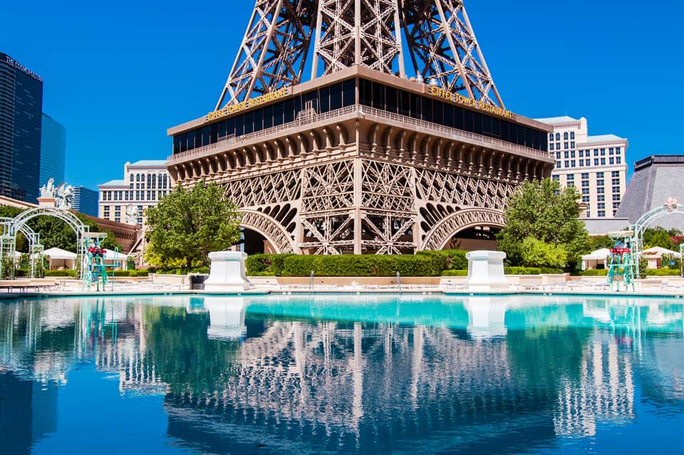 Half-scale Eiffel Tower replica reflected in pool at Las Vegas resort with surrounding hotels