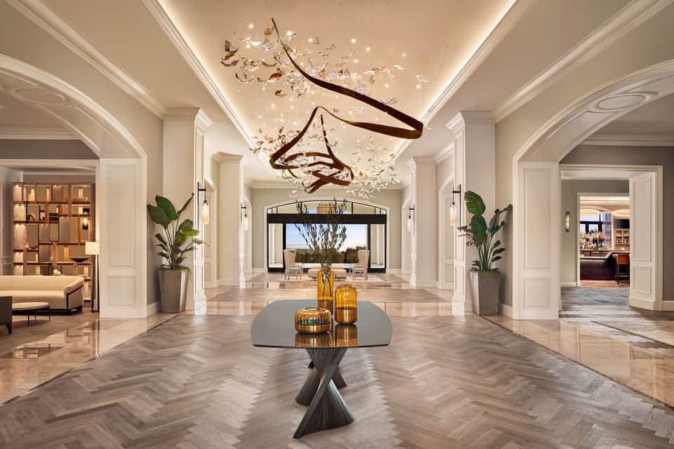 Luxurious hallway with coffered ceiling, artistic chandelier, and marble herringbone flooring