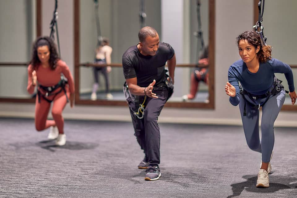 Group fitness class with participants doing suspension training exercises in a modern gym facility