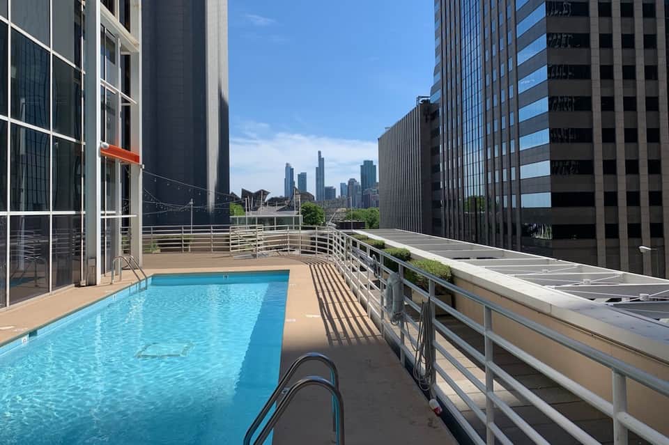 Rooftop swimming pool with city skyline view surrounded by modern high-rise buildings