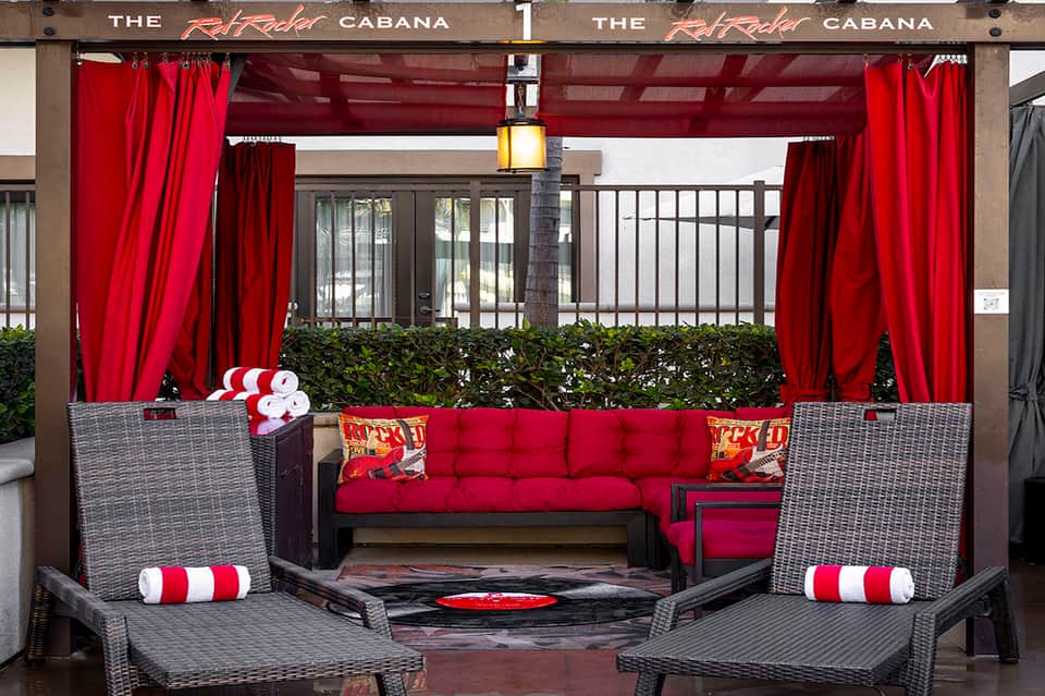 Red cabana lounge area with draped curtains, wicker chairs, and red cushioned seating