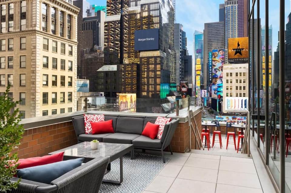 Urban rooftop terrace overlooking Times Square with lounge seating and skyline views