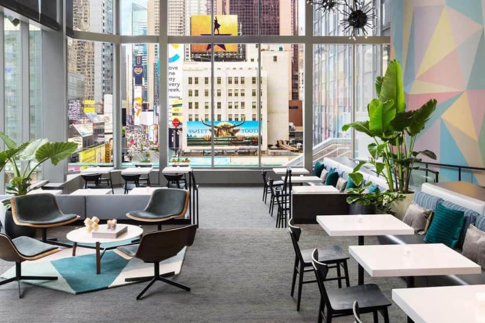 Contemporary lounge with floor-to-ceiling windows overlooking a busy downtown cityscape