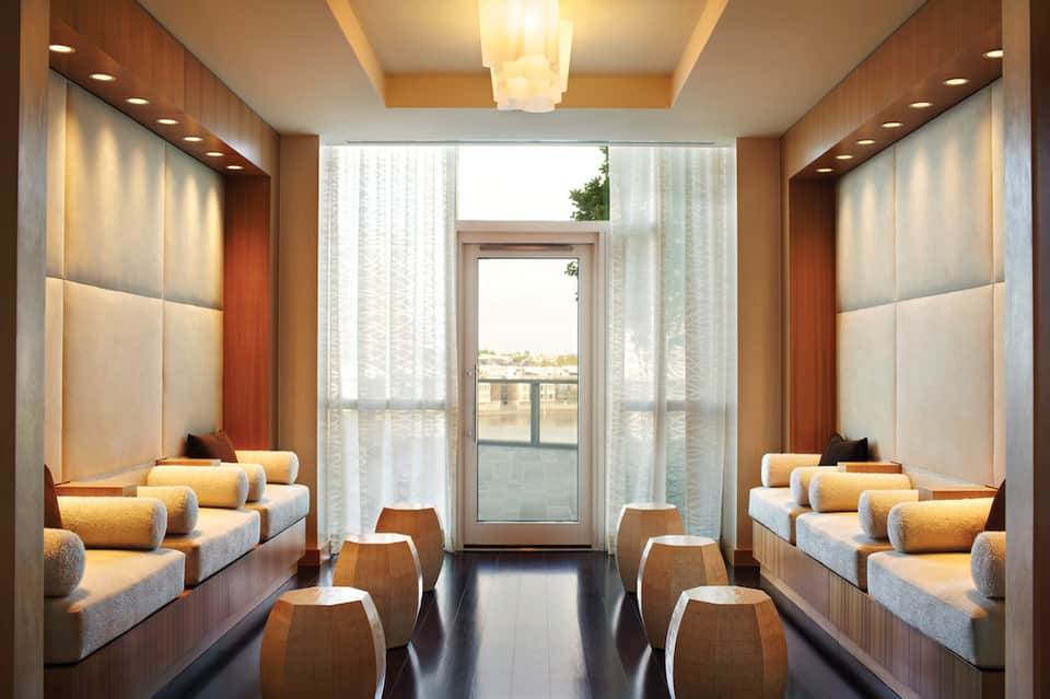 Contemporary spa relaxation room with built-in benches, cushions, and glass doors overlooking a balcony