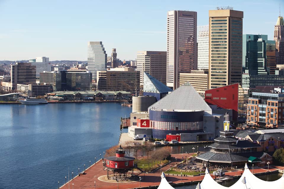 Urban waterfront cityscape with high-rise buildings and red-roofed arena structure