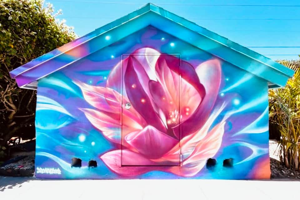 Colorful garage door mural featuring a glowing pink lotus flower on blue background