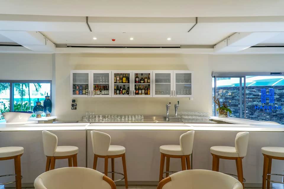 Modern bar with white counter, cream bar stools, and city views through large windows