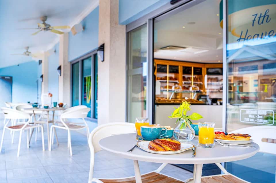 Bright breakfast dining area with fresh pastries, juice, and coffee at a white table