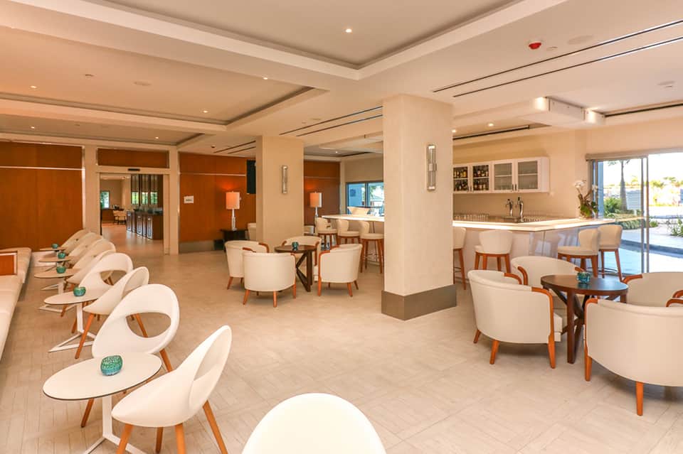 Modern hotel lounge with cream seating, wooden accents, and ocean views through large windows