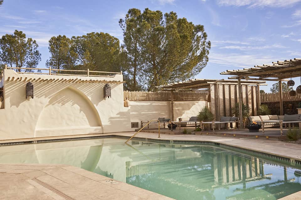 Resort spa pool with white architectural features, wooden pergolas, loungers, and desert landscaping