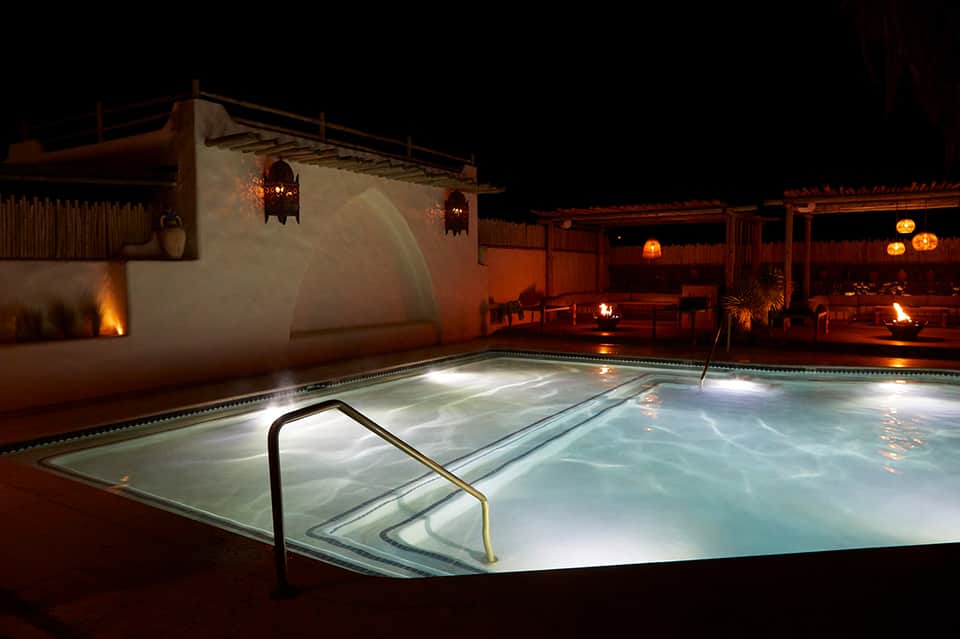 Illuminated hot tub at night with modern architectural design and warm ambient lighting in desert setting