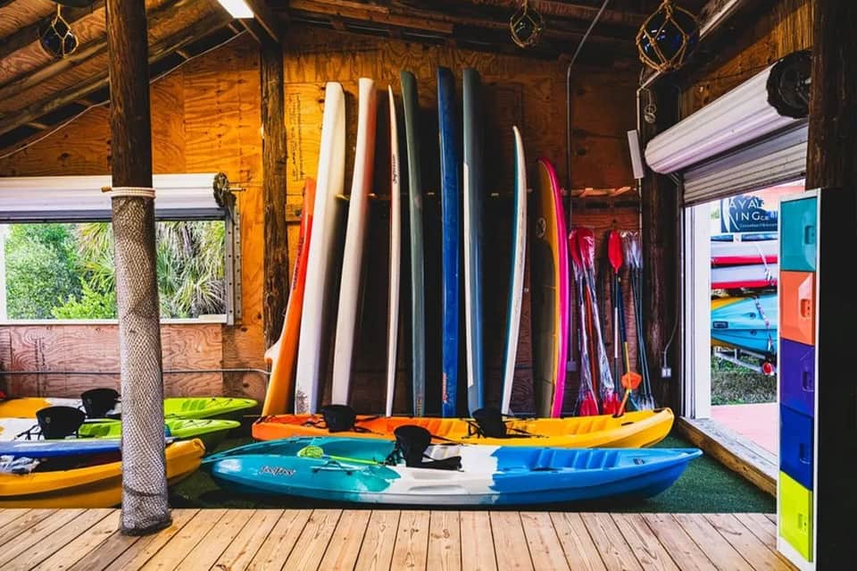 Indoor water sports rental shop displaying colorful surfboards and kayaks in wooden structure