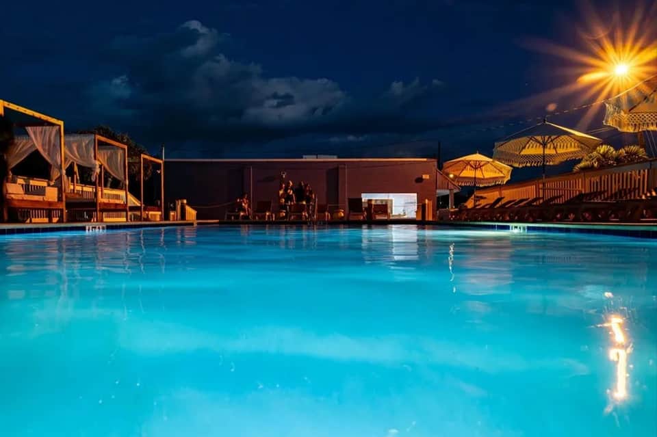 Luxurious resort pool at dusk with illuminated cabanas, umbrellas, and modern architecture