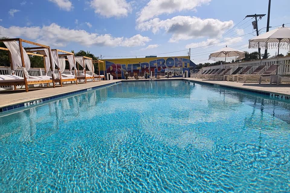 Resort swimming pool with cabanas, umbrellas, and beachfront setting
