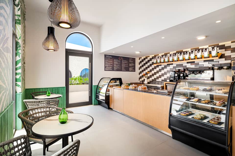 Modern café interior with green accent wall, pendant lighting, counter service, and checkered tile backdrop