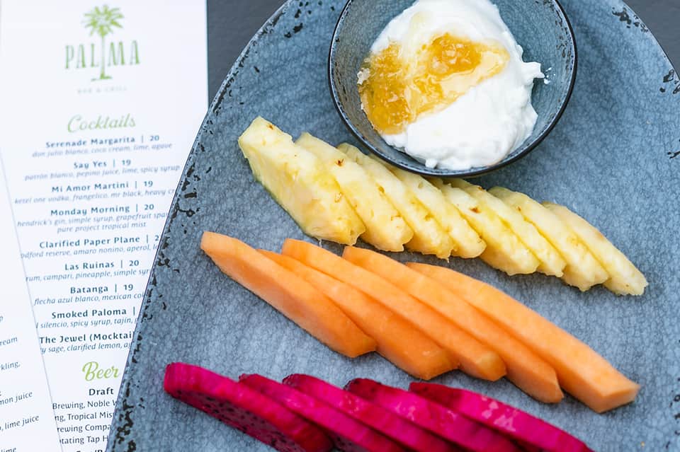 Gourmet appetizer plate with sliced pineapple, salmon, carrots, and whipped cream with menu