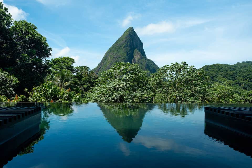 Dramatic mountain peak reflected in still water surrounded by lush tropical forest and wooden docks