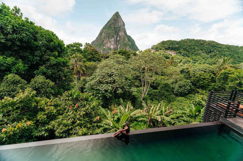 Infinity pool overlooking lush green jungle landscape with distinctive peaked mountain formation in distance